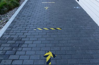 Sosyal uzaklık çizgileri ve okları insanlara sosyal mesafeyi hatırlatmak için bir dükkanın önündeki kaldırıma yapışmış.