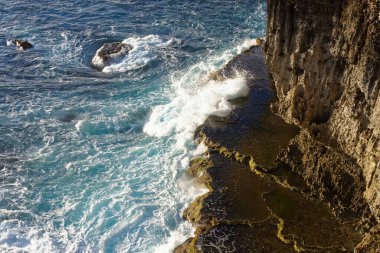 Uçurumun dibindeki kayalara çarpan deniz.