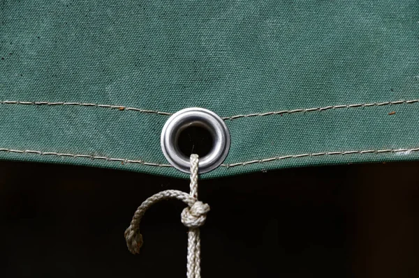 A metal eyelet in a tarpaulin keeps it securely fastened