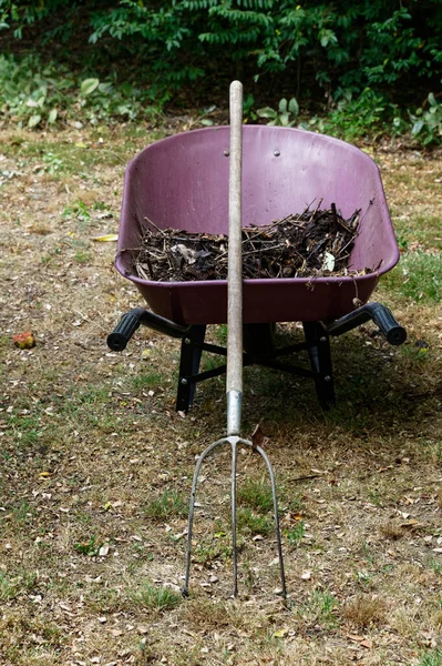 Compost Una Carretilla Roja Borgoña Tiene Una Horquilla Apoyada Ella — Foto de Stock