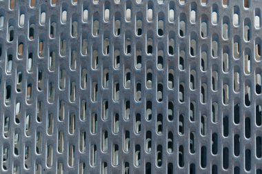 Sıralarda yuvarlak delikleri olan gümüş bir metal ızgara.