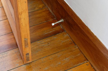 Tahtaya bağlı metal bir yay kapı tıpası ile ahşap bir kapının duvara çarpmasını engeller.