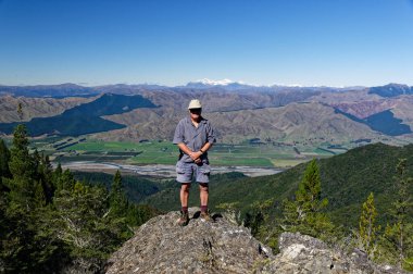 Bir adam Yeni Zelanda 'nın büyük açıklarında kayalık bir çıkıntıda duruyor.
