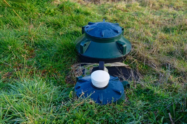 Blue tops of a septic tank system can be seen above the grass