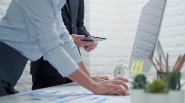 İki iş adamı iş yerindeki belgelerin analizlerini ve diyagramlarını inceliyor.