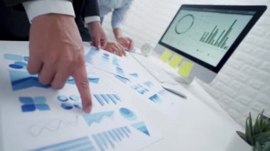 İki iş adamı iş yerindeki belgelerin analizlerini ve diyagramlarını inceliyor.