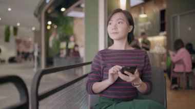 Kafede akıllı telefon kullanan mutlu Asyalı kadın.