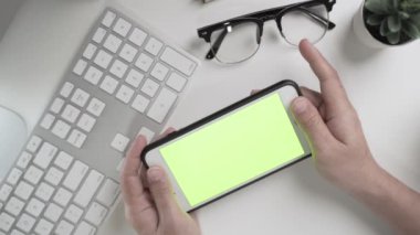 İş kadınının elleri çalışıyor ve akıllı telefondaki yeşil ekrana dokunuyor.