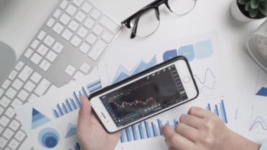 İş kadınının elleri çalışıyor ve grafik veri belgesi ile akıllı telefon kullanıyor