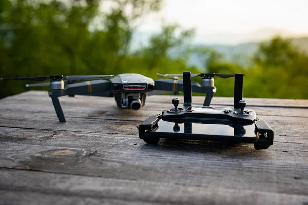 DJI Mavic, ahşap bir masadaki kumandaya bağlı cep telefonu olan profesyonel drone.