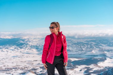 Arka planda güzel bir dağ manzarasının önünde poz veren güzel bir sporcu kadın.