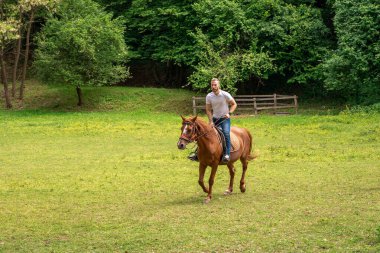 Genç adam çiftlikte at binmekten hoşlanıyor.