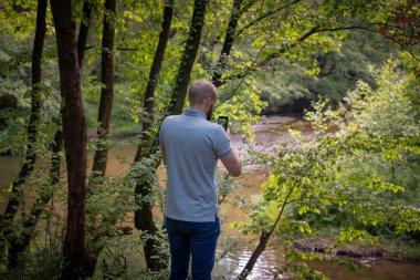 Genç yetişkin bir nehrin fotoğrafını çekiyor.