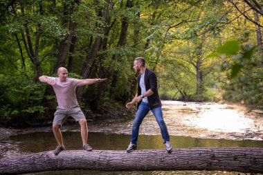 Kütük bir köprüde dövüş sanatları yapan iki çocuk.