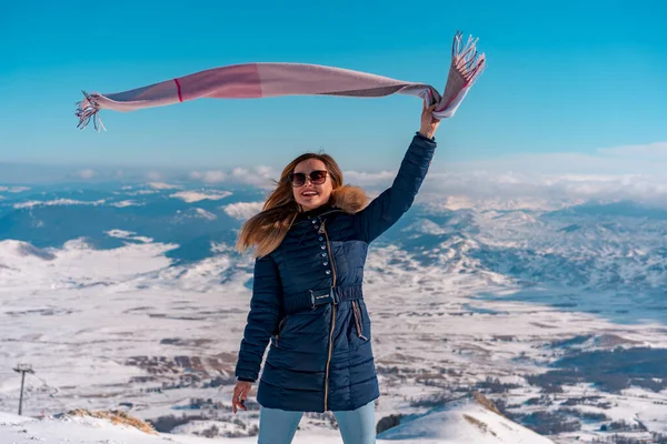 Güzel bir kadın arka planda muhteşem vahşi dağ manzarasıyla eşarbını sallıyor.