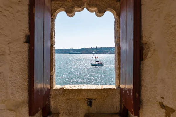 Small boat seen through an old window of an ancient fort