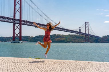 Lizbon 'daki ünlü köprünün önüne atlayan kırmızı elbiseli genç kadın.