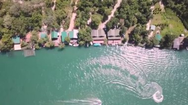 Nehirdeki farklı denizcilik gemilerinin ve kıyı şeridi boyunca bulunan bungalovların insansız hava aracı görüntüsü