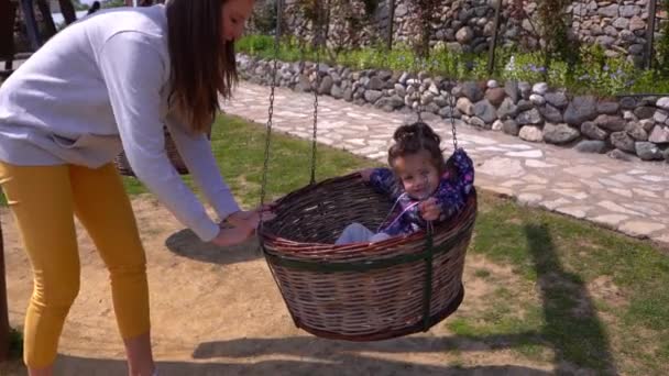 母プッシュ彼女の小さな娘で木のバスケットスイング — ストック動画