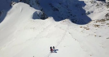 Dağ rehberi iki kadın yürüyüşçüye Durmitor 'daki donmuş yürüyüş yolunu takip etmeleri için yardım ediyor.