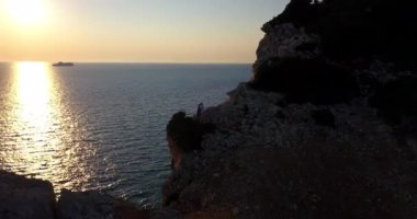 Gün batımında Lefkas Burnu 'nda bir uçurumun kenarında duran çift.