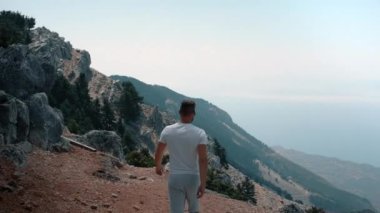 Genç adam Kefalonia adasının tepesinden, Ainos Dağı 'ndan büyüleyici manzaranın tadını çıkarıyor.