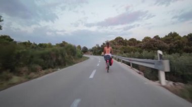 Hvar adasındaki boş bir yolda bisiklet süren genç bir kız.