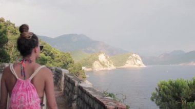 Genç bir kadın yürüyor ve uzaktaki güzel manzaraya hayran.