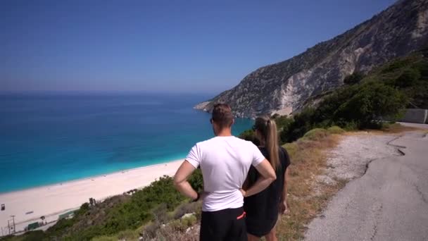 一对年轻夫妇在Kefalonia的Myrtos海滩上欣赏风景 — 图库视频影像