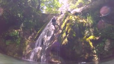 Dik bir şelaleden iple inen adam