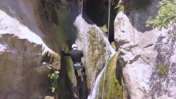 峡谷で大規模な滝を下る男のドローンショット — ストック動画