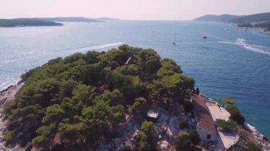 Hvar 'daki çok küçük bir adanın tepesinde rüzgarda dalgalanan Hırvat bayrağının havadan görünüşü