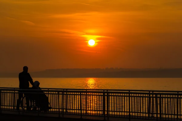 Disabled woman with her son on pier at sunset — Stock Photo, Image