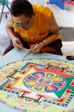 Tibetli keşiş renkli bir Kum Mandala üzerinde dikkatle çalışıyor. 