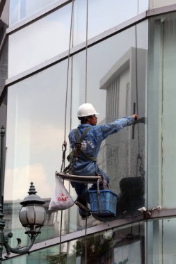 Ofis pencerelerini temizleyen adam. Vietnam. 