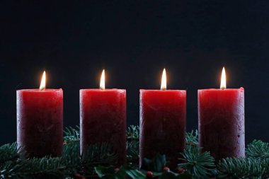 Dört yanan kırmızı mumlu doğal bir çelenk ya da taç. Noel kompozisyonu.