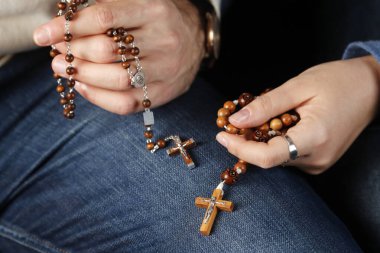 Katolik bir adam ve kadın evde birlikte dua ediyorlar. Dua boncuklarıyla ellerini kapat. Fransa. 