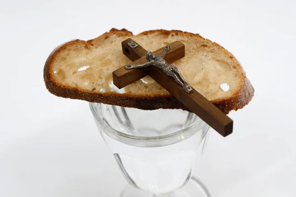 Lent starts on Ash Wednesday and ends on Holy Thursday Evening. Glass of water, christian cross and bread. France.