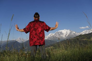 Mont Blanc 'ın önünde Qi Gong ya da Tai Chi egzersizi yapan bir kadın. Fransız Alpleri. 