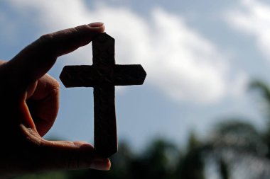 Christian cross against the sky. Close-up on hand.  Kep. Cambodia. clipart