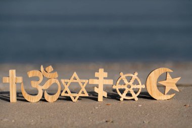 Religious symbols on sand. Christianity, Islam, Judaism, Orthodoxy Buddhism and Hinduism. Interreligious or interfaith concept clipart