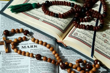 Hristiyanlık ve İslam dünyanın en büyük iki dinidir. İncil, Kuran. Haç ve tespih. Dinlerarası semboller.