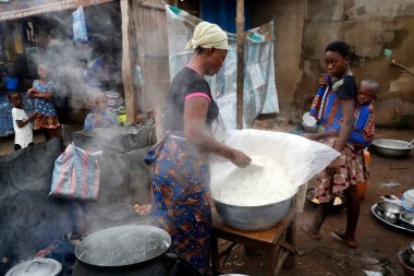 Sokak restoranında pilav pişiren Afrikalı bir kadın. Benin.. 