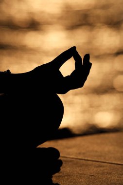 Nilüfer pozisyonunda meditasyon yapan genç bir kadının elini kapat. Gün batımında yoga.. 