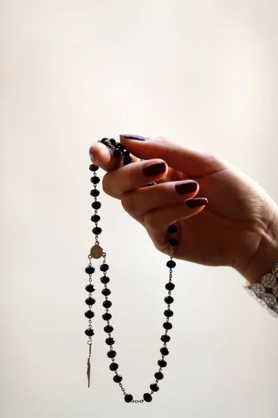 Catholic woman praying with rosary beads. Close-up on hand.