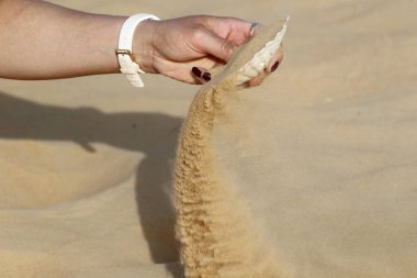 Çölde deniz tarağı kabuğundan kum çıkaran bir kadının el yapımı görüntüsü. Din, inanç, dua ve maneviyat kavramı.?
