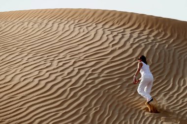 Kadın ayak izleri bırakıyor ve çöl kum tepesine çıkıyor. Dubai 'de. Birleşik Arap Emirlikleri.