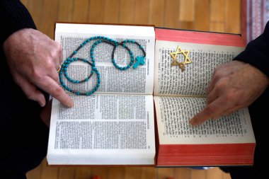 İki tek tanrılı din, Hristiyanlık ve Yahudilik. Tevrat 'ı ve İncil' i okuyan bir Yahudi ve Hıristiyan. Dinler arası diyaloğun sembolü..