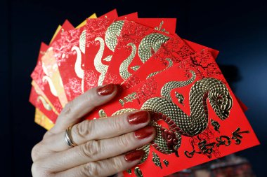 Çin ve Vietnam 'ın yeni yıl kutlamaları için kırmızı zarflı Asyalı kadın. Kırmızı renk iyi şansın sembolüdür. Yılan Yılı.