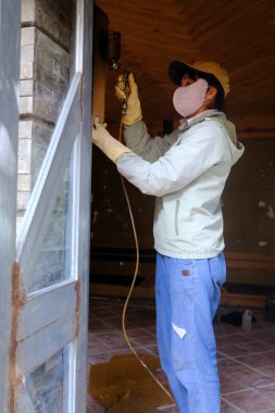 İnşaat alanında çalışan bir kadın. Bir evin tadilatı. Sprey boya. Kontum. Vietnam.